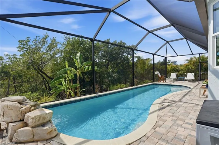 Outdoor pool with a sunroom, a patio, and glass enclosure - Virtually Edited Image