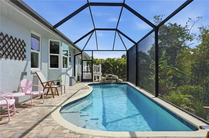 Swimming pool featuring a sunroom, glass enclosure, and a patio area - Virtually Edited Image