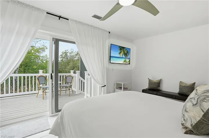 Bedroom featuring multiple windows, access to exterior, and ceiling fan - Virtually Edited Image