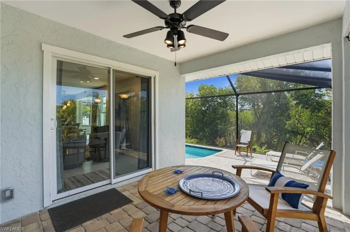 View of patio featuring an outdoor pool, a lanai, a sunroom, and a ceiling fan - Virtually Edited Image