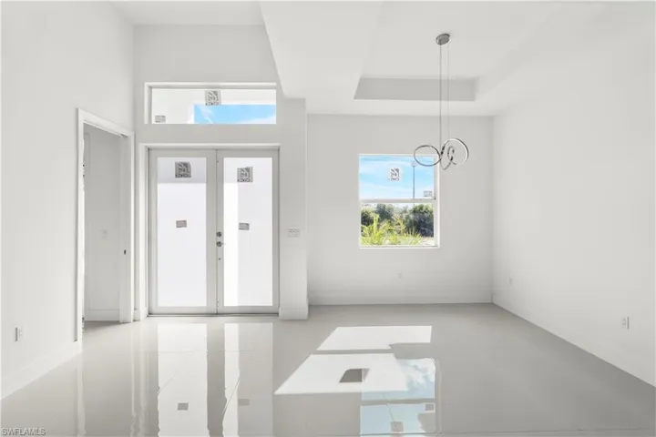 Foyer entrance featuring french doors, a chandelier, and a raised ceiling