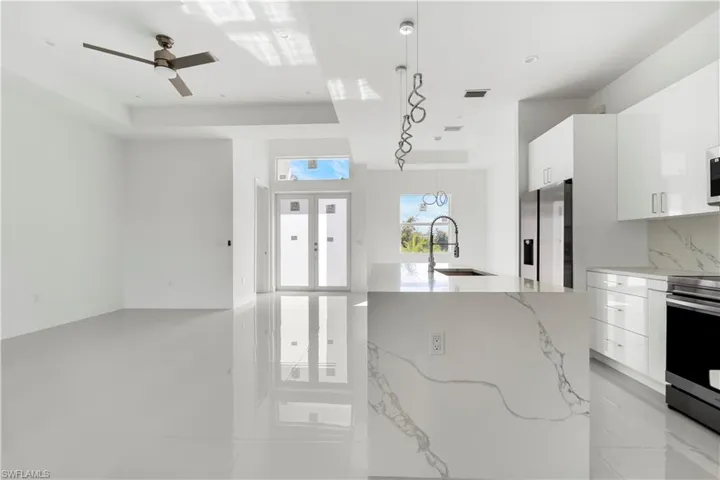 Kitchen with modern cabinets, white cabinetry, and light stone counters