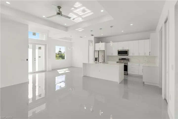 Kitchen with white cabinetry, tasteful backsplash, stainless steel appliances, hanging light fixtures, and light stone countertops