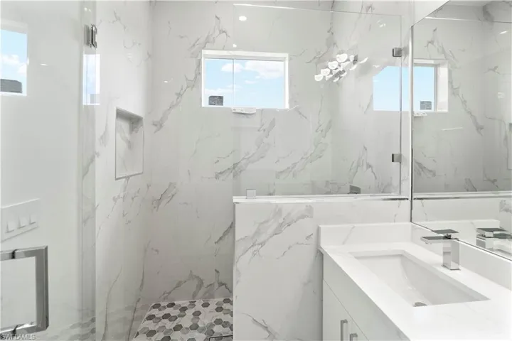 Bathroom featuring vanity, plenty of natural light, and a marble finish shower