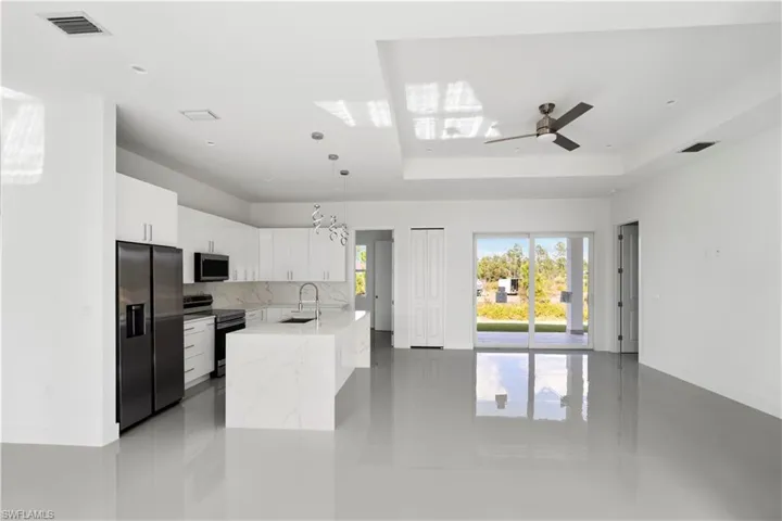 Kitchen with appliances with stainless steel finishes, white cabinets, a chandelier, pendant lighting, and tasteful backsplash