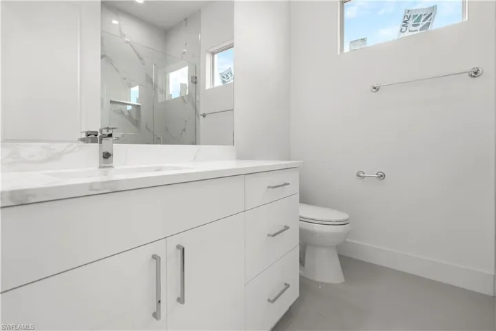Bathroom featuring vanity and a marble finish shower