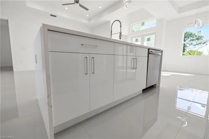 Kitchen view of modern cabinets, a tray ceiling, stainless steel dishwasher, pendant lighting, and recessed lighting