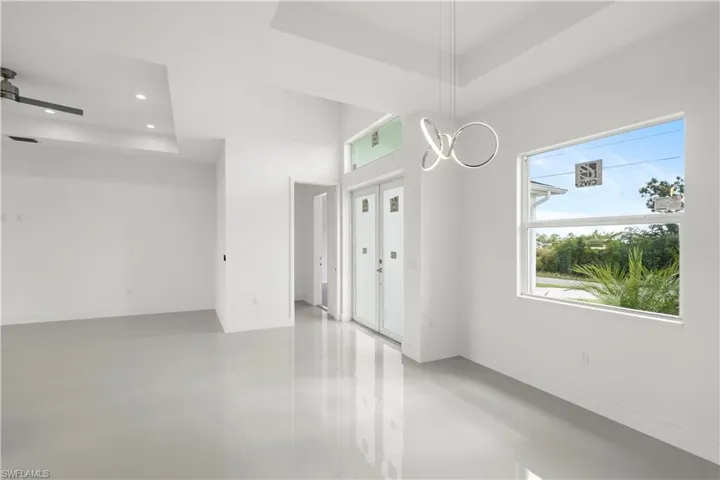 Unfurnished room with a tray ceiling, concrete flooring, and recessed lighting