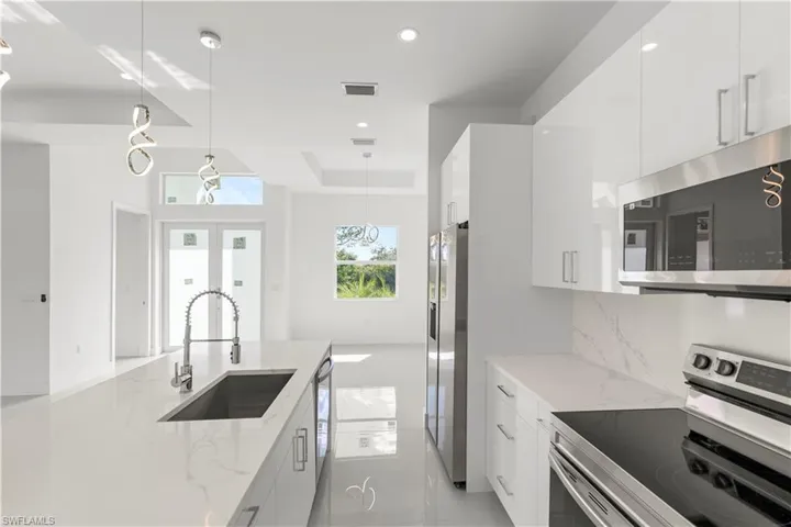 Kitchen with appliances with stainless steel finishes, hanging light fixtures, modern cabinets, light stone countertops, and recessed lighting