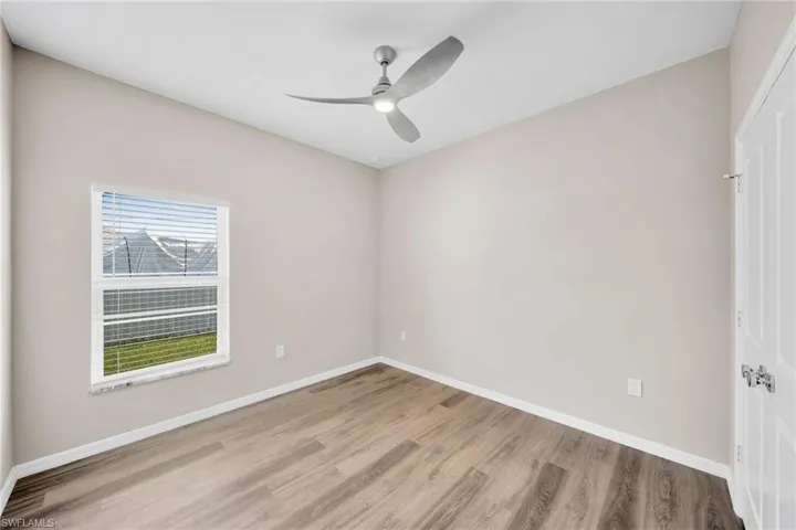 Unfurnished bedroom featuring a closet, baseboards, wood finished floors, and a ceiling fan