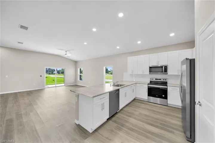Kitchen featuring tasteful backsplash, visible vents, open floor plan, a wealth of natural light, and stainless steel appliances