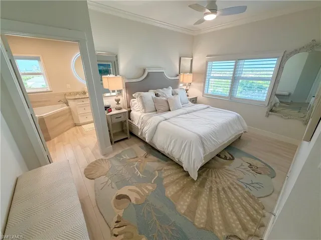 Bedroom featuring ornamental molding, multiple windows, ceiling fan, light wood-style floors, and ensuite bathroom