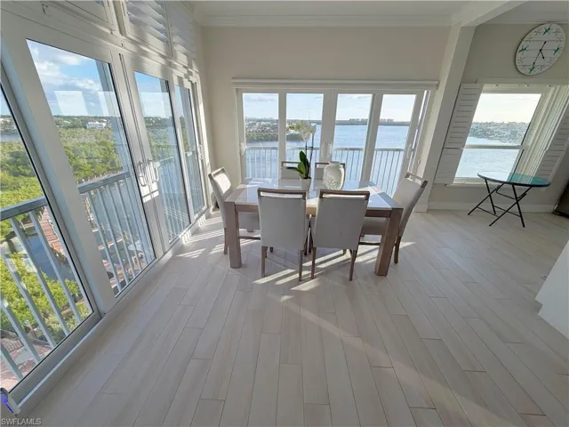 Sunroom / solarium featuring a water view, plenty of natural light, ornamental molding, and wood finished floors