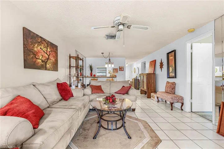 Living room with a textured ceiling, tile patterned floors, and a ceiling fan