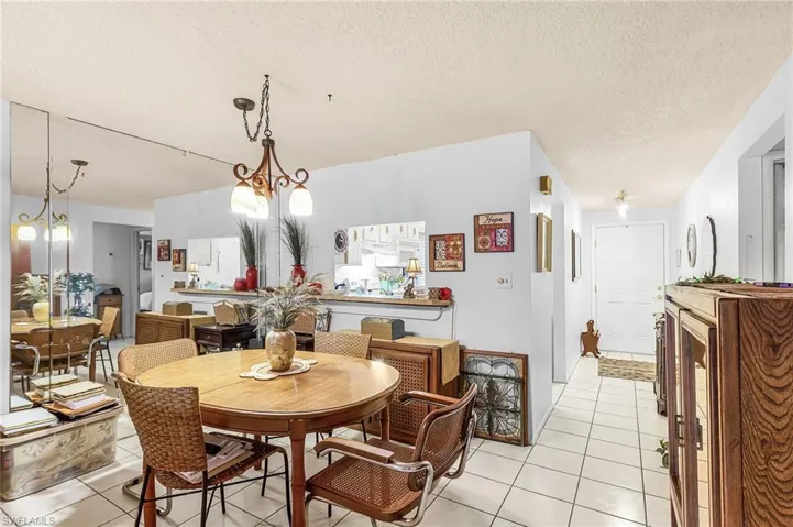 Dining area with light tile patterned floors, a chandelier, and a textured ceiling