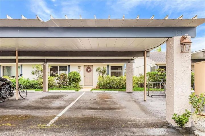 Doorway to property featuring covered parking and stucco siding