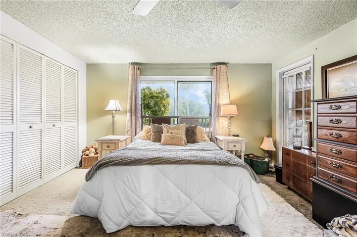 Bedroom with a textured ceiling, a closet, a ceiling fan, and carpet floors