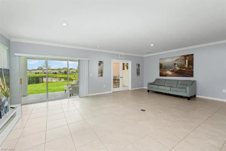 Unfurnished living room featuring crown molding, a water view, light tile patterned floors, and recessed lighting