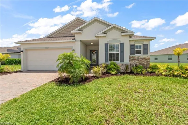 View of front of property featuring stucco siding, decorative driveway, a garage, and a front lawn