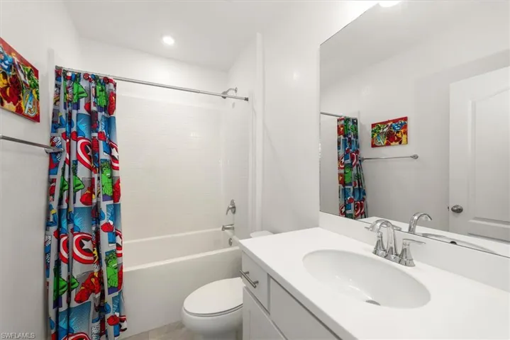 Full bathroom with vanity, shower / bathtub combination with curtain, and recessed lighting
