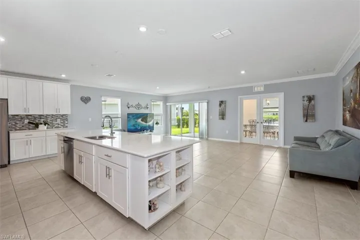 Kitchen with open floor plan, crown molding, light tile patterned floors, backsplash, and appliances with stainless steel finishes
