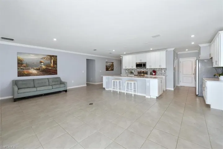 Living area featuring crown molding, light tile patterned flooring, and recessed lighting