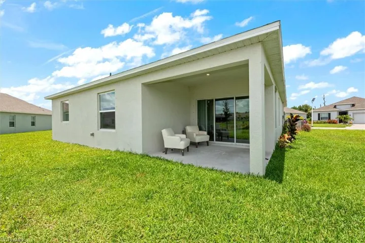 Rear view of house featuring stucco siding, a patio, and a yard