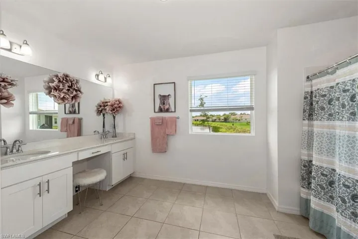 Full bathroom with double vanity, tile patterned floors, and a shower with shower curtain