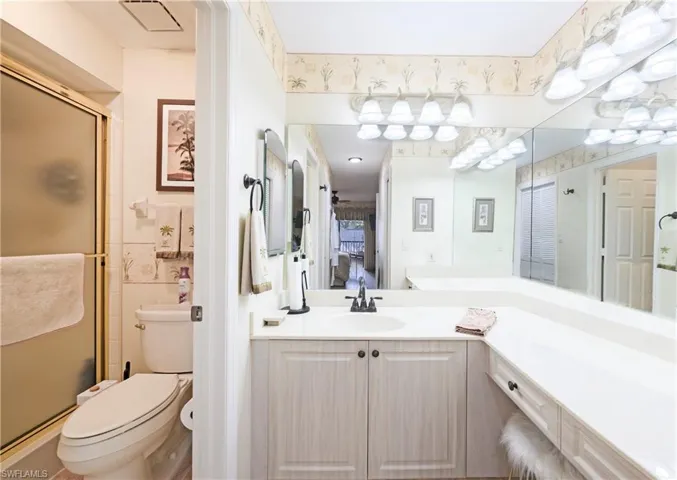 Bathroom featuring toilet, vanity, and walk in shower