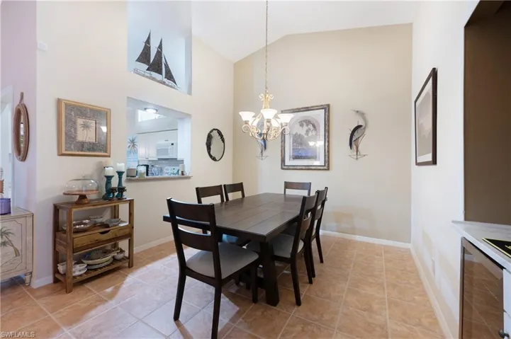 Tiled dining space with wine cooler, high vaulted ceiling, and a notable chandelier