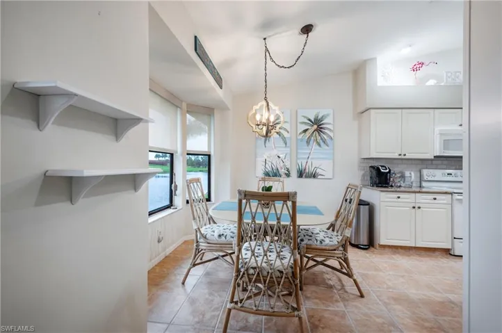 Tiled dining space featuring vaulted ceiling and a notable chandelier