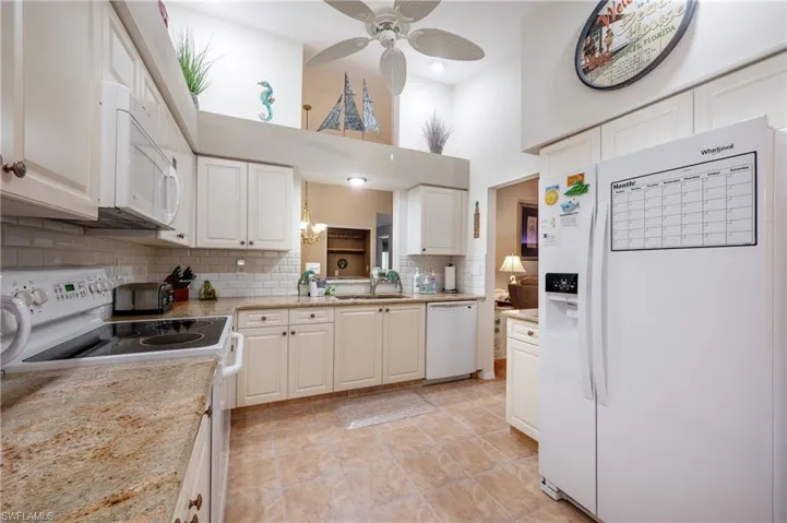 Kitchen featuring a towering ceiling, white appliances, white cabinetry, and backsplash