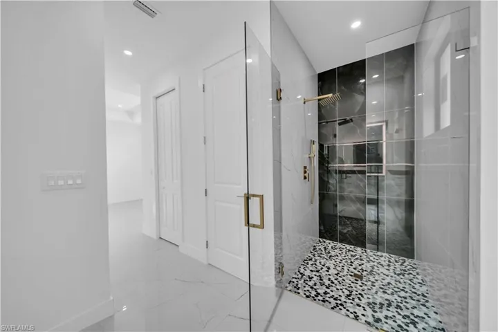 Bathroom featuring a marble finish shower, marble finish floors, and recessed lighting