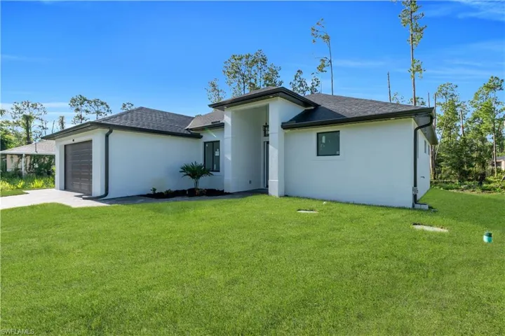 View of front of home featuring a front yard, a garage, and roof with shingles