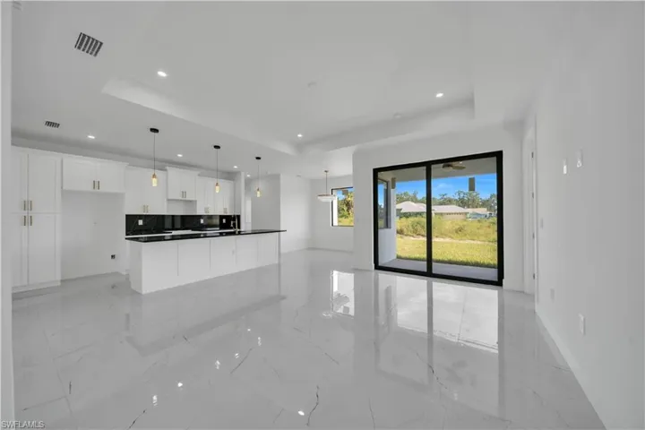 Unfurnished living room with light marble finish floors, a raised ceiling, and recessed lighting