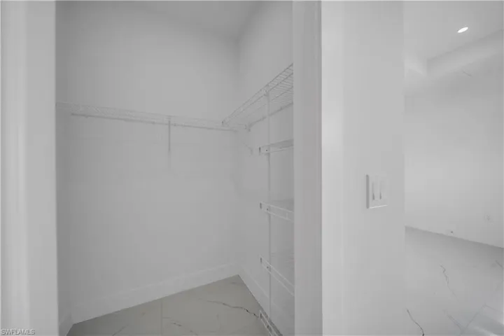 Walk in closet featuring light marble finish floors