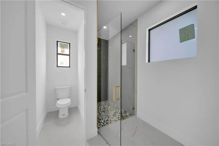 Bathroom with a marble finish shower, marble finish flooring, and recessed lighting