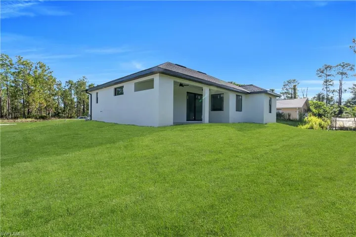 Rear view of property with a yard, stucco siding, and a ceiling fan