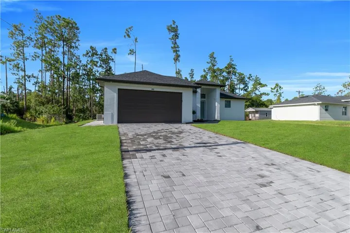 View of front facade featuring decorative driveway, a front lawn, a garage, and stucco siding