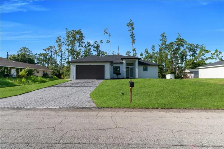 View of front facade with decorative driveway, a front yard, an attached garage, and stucco siding