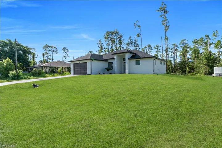 View of front of home with a front yard, an attached garage, stucco siding, and driveway