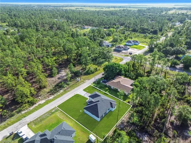 Aerial view of residential area featuring property boundaries highlighted and a heavily wooded area