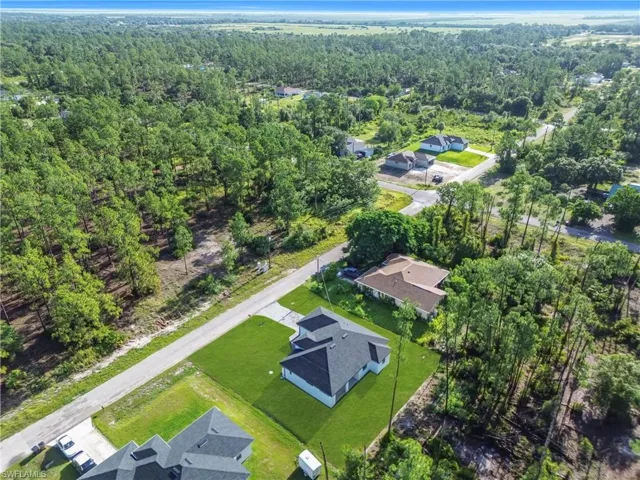 Aerial overview of property's location with a forest and nearby suburban area