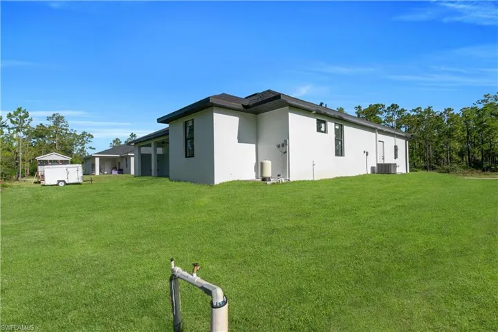 Rear view of house featuring a lawn and stucco siding