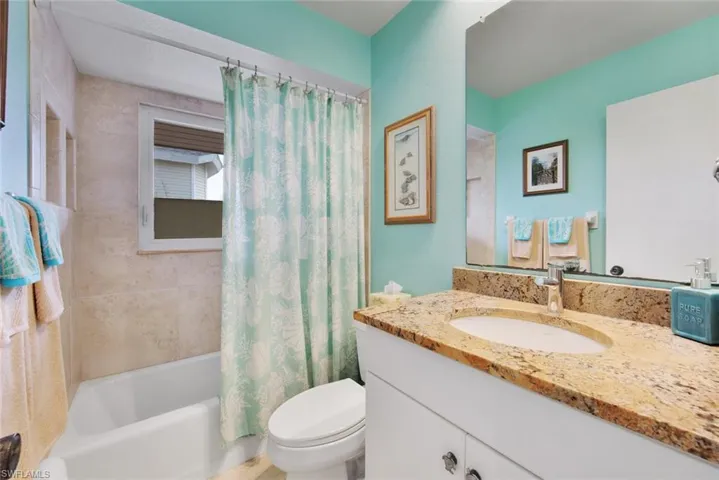 Full bathroom with toilet, shower / tub combo with curtain, and vanity