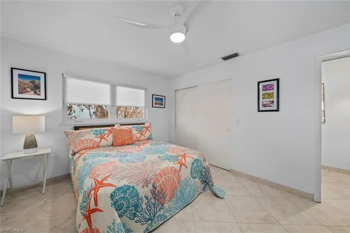 Bedroom with light tile patterned flooring, ceiling fan, and a closet