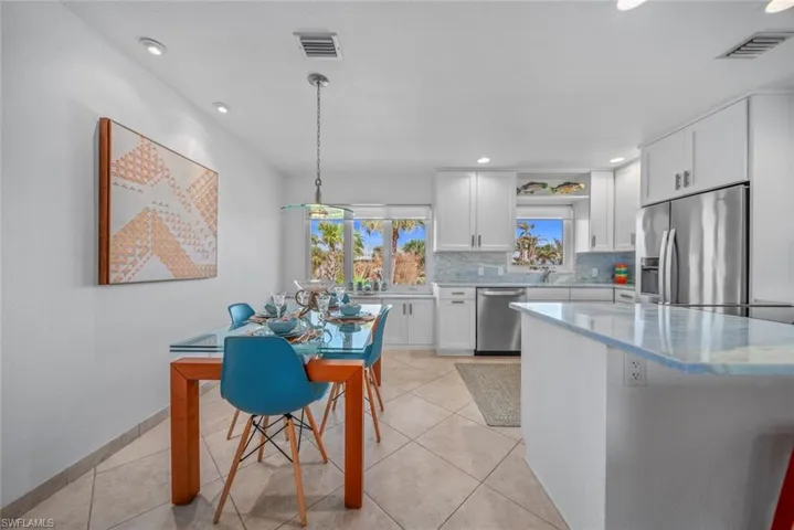 Kitchen featuring stainless steel appliances, pendant lighting, sink, tasteful backsplash, and white cabinetry