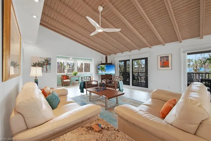 Tiled living room featuring high vaulted ceiling, a healthy amount of sunlight, ceiling fan, and wood ceiling
