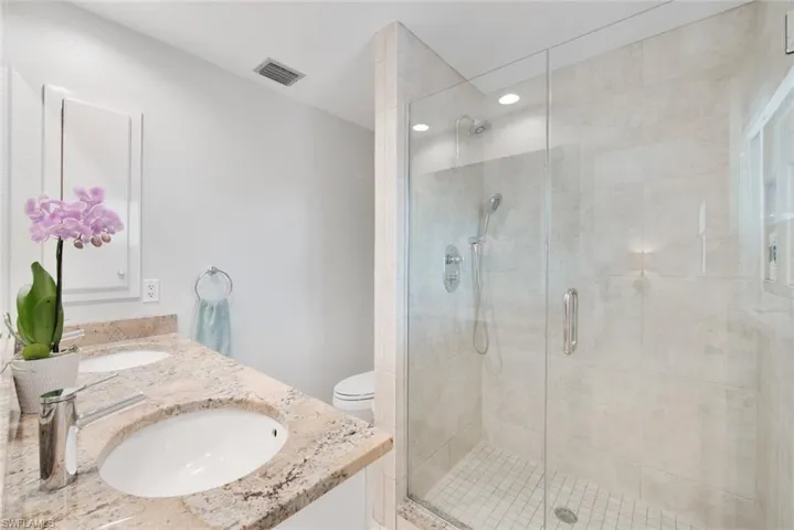 Bathroom with toilet, vanity, and an enclosed shower
