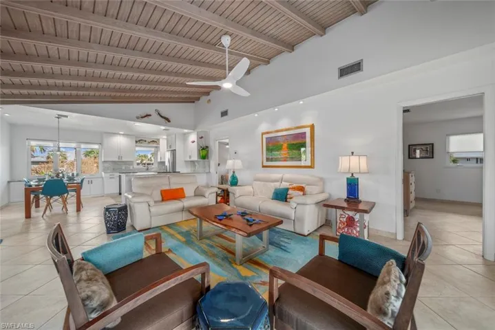 Tiled living room with high vaulted ceiling, beamed ceiling, wood ceiling, and ceiling fan